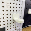 White pegboard Apple Watch charger holder mounted on a white round-hole panel.
