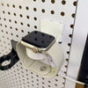 Close view of an Apple Watch on the white charger holder mounted to a round-hole pegboard.