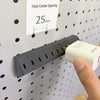 Black and white charger adapter holders mounted on a pegboard beside charging cables and a 25 mm spacing label.