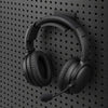 Black gaming headset resting on a KOKO pegboard headset holder, with the earcups hanging below.