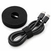 Black hook-and-loop fastening tape wrapped around a coiled USB-C cable, with a tape roll beside it on a white background.