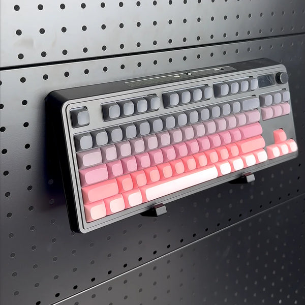 Gray and pink keyboard resting on two black pegboard support brackets
