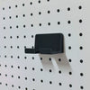 Black KOKO Pegboard phone holder mounted empty on a white round-hole pegboard.