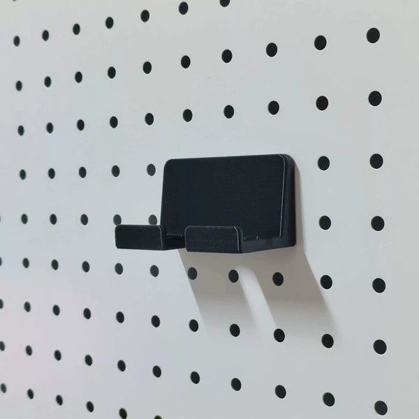 Black KOKO Pegboard phone holder mounted empty on a white round-hole pegboard.