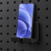 Black KOKO pegboard phone holder supporting a smartphone on a round-hole panel. Phone is a display prop and is not included.